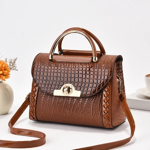 Détail de la texture crocodile sur sac à main marron avec poignée et fermoir dorés