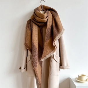 Detail of thick cashmere-like scarf with brown checkered pattern and fringe tassels