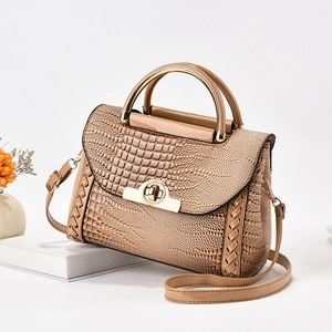 Détail d'un sac à main gaufré crocodile avec poignée métallique et bords tressés