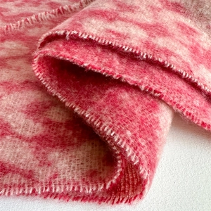 Close-up of pink and white leopard pattern knit scarf with soft fringe and plush texture