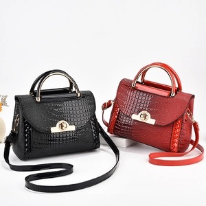 Détail de sacs à main rouge et noir à motif crocodile avec poignées en métal doré