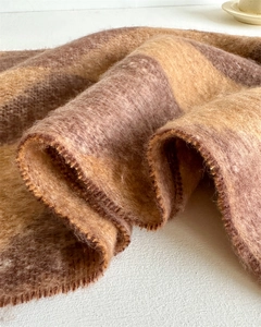 Close-up of thick checkered scarf showing fluffy faux cashmere texture and camel tones