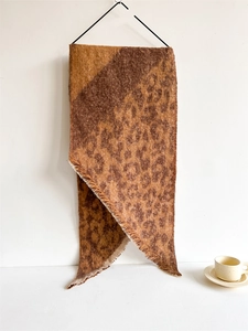 Detailed view of leopard print knit scarf with fringe edges and soft texture
