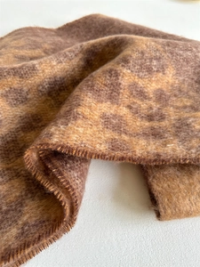 Detailed view of leopard print boucle scarf showing long plush texture and whip-stitch edge