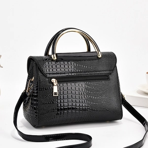 Détail d'un sac à main motif crocodile avec poignées en métal doré et poche zippée
