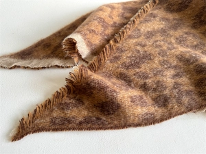 Close-up of leopard print scarf featuring thick bouclé texture and frayed tassel edges