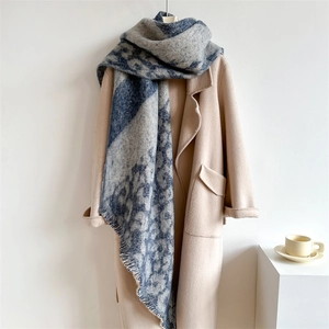 Close-up of leopard pattern thick knit scarf with short fringes on beige coat