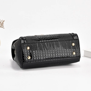 Détail de la base en cuir croco avec pieds dorés de protection sur le sac à main noir