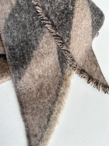 Detailed close-up of thick checkered winter scarf with soft fringe and fiber texture