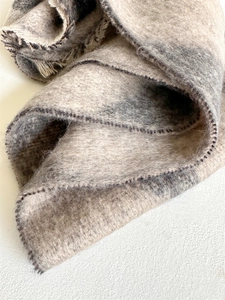 Detail shot of plush checkered scarf with handmade lockstitch edges and soft fringe tassels