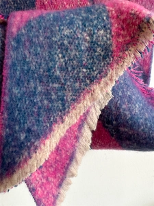 Close-up of thick checkered cashmere-like scarf with fringe in rose red and blue