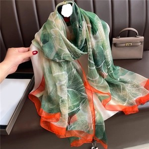 Close-up of silk scarf with artistic green abstract patterns and orange rolled edges