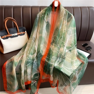 Detail of elegant gradient green silk shawl with floral prints and orange contrast edges