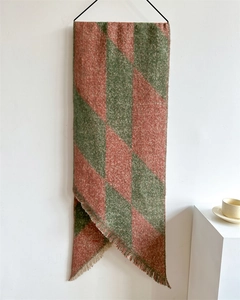 Close-up of green and coral checkered knit scarf with soft fringe details and thick texture