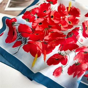 Detail of silk scarf with red poppy floral print and navy blue rolled edges