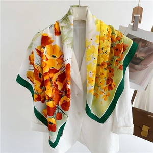 Detail of 90cm floral silk scarf with orange flowers and green border on a white blazer