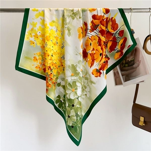 Close-up of floral silk scarf with green borders hanging beside a leather handbag