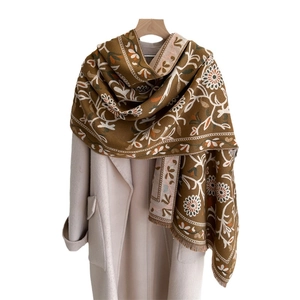 Caramel brown scarf with floral embroidery and fringe trim on a beige wool coat