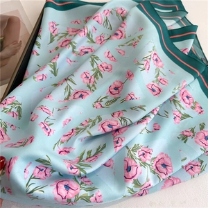 Detail of silk scarf with floral patterns, soft satin texture, and elegant edge border