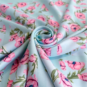 Macro view of floral silk scarf featuring pink blossoms on a light blue fabric texture