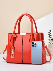 Elegant red faux leather handbag with gold accents and shoulder strap for daily work