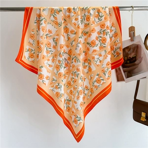Detail of orange floral silk scarf with geometric patterns and double-colored border