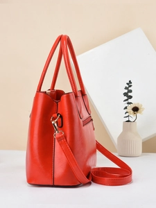 Chic red faux leather tote bag with gold hardware and adjustable strap shown in a studio