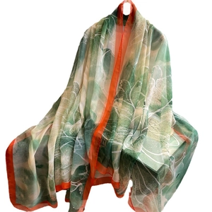Large silk-feel shawl with green floral print and orange borders for sun protection