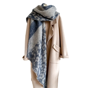 Blue animal print scarf with fringe edges paired with a chic beige coat for winter warmth