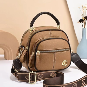 Deep khaki pebbled leather crossbody bag with triple zippers and patterned strap