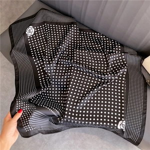 Detailed view of polka dot and camellia print on glossy satin square scarf