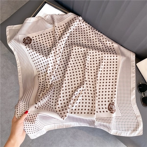 Close-up of polka dot silk scarf with brown roses and neat rolled edges on fabric