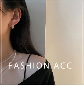 Détail de la boucle d'oreille dorée texturée portée avec un collier de perles