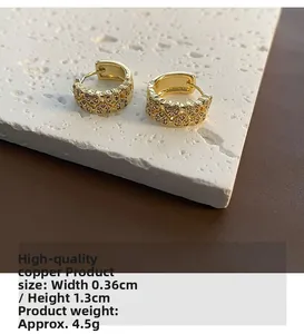 Détail de boucles d'oreilles cœur dorées avec zircons sur un support en pierre