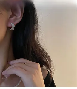 Détail de créoles en argent s925 avec zircons portées par un mannequin au look chic