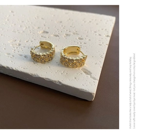 Détail macro de boucles d'oreilles créoles cœur dorées serties de zircons brillants