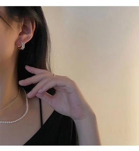 Détail de boucles d'oreilles cœur en zircon et colliers de perles superposés sur mannequin