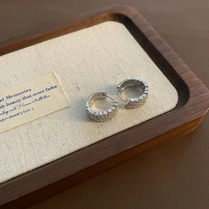 Boucles d'oreilles cœur en argent avec zircons sur un plateau de présentation en lin