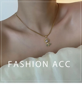 Dettaglio della collana con ciondolo a girasole e zirconi su catena a serpente dorata