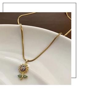 Dettaglio del ciondolo a girasole con zirconi colorati su una catena a serpente dorata