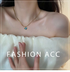 Detailed view of a golden heart necklace with abalone shell inlay on a female model