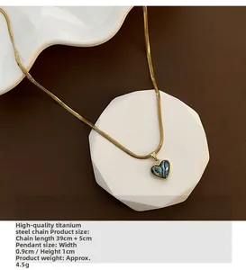 Macro detail of heart-shaped abalone shell pendant on gold plated snake bone chain necklace