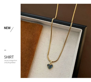 Macro shot of gold heart necklace with abalone shell inlay on beige textured jewelry box