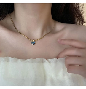 Detail of heart shell pendant necklace on woman neck in gold tone finish