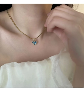 Close-up of a heart-shaped abalone shell pendant on a gold snake chain necklace