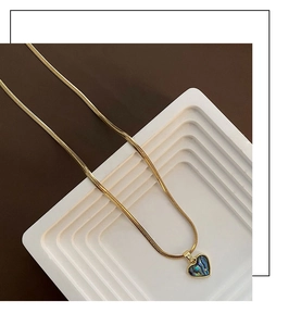 Macro shot of heart-shaped abalone shell pendant necklace on golden snake chain