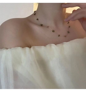 Gros plan d'un collier en titane avec pierres naturelles vertes sur chaîne dorée