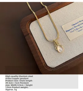 Détail macro du pendentif goutte en nacre et zircons posé sur un plateau en bois