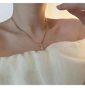 Détail du pendentif feuille avec opale sur une chaîne serpent dorée portée par un mannequin
