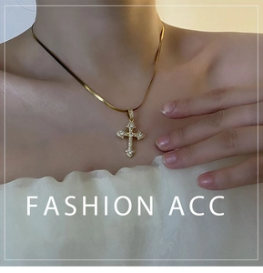 Détail d'un collier chaîne serpent dorée avec pendentif croix orné de zircons blancs